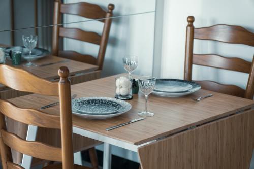 メルボルンにあるThe Meow Empire Cat-Themed Stay with Cityview Poolの皿とワイングラスが置かれた木製のテーブル