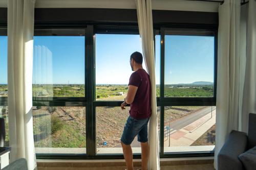 een man die uit het raam van een huis kijkt bij Apartamento familiar en Torreblanca con vistas al mar, aire acondicionado y cerca de la playa in Torreblanca