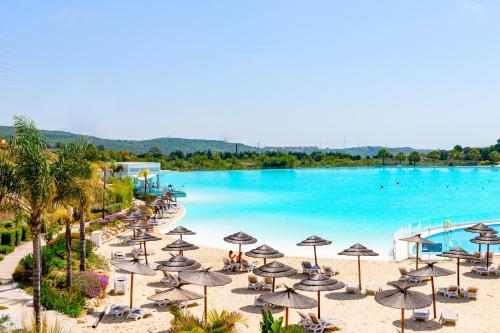 een uitzicht op een strand met parasols en een zwembad bij Alcazaba Lagoon Apartment with Private Beach, Pools, Gym, Sauna, Hot Tub & Fully Equipped Kitchen in Casares