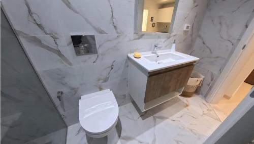 Un baño blanco con inodoro y lavabo. en Farah, en Sousse