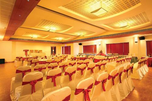 a banquet hall with white chairs and red bows at Hotel Park Residency, Kakkanad in Kakkanad