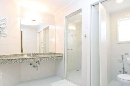 uma casa de banho branca com um chuveiro e um WC. em Pousada Portal das Cerejeiras by Platanus em Campos do Jordão