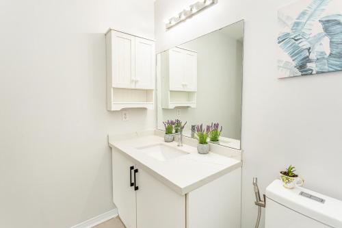 ein weißes Badezimmer mit Waschbecken und Spiegel in der Unterkunft House of 3 Bed 3 Wash-Crib-King Bed-85' TV-Wrkspce in Oakville