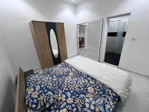 1 dormitorio con 1 cama con manta azul y espejo en Keur joie, en Mbour