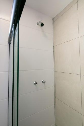 a shower with white walls and a glass door at Xavi Studio - Sem Vaga de Garagem in Bauru