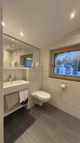 a bathroom with a sink and a toilet and a window at Hotel Sailer in Sankt Anton am Arlberg