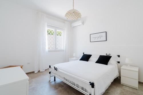 une chambre blanche avec un lit blanc avec des oreillers noirs dans l'établissement Villa Greta, à Isola della Malva