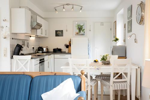 Ferienhaus Irle في Neukirchen: مطبخ مع خزائن بيضاء وطاولة وكراسي