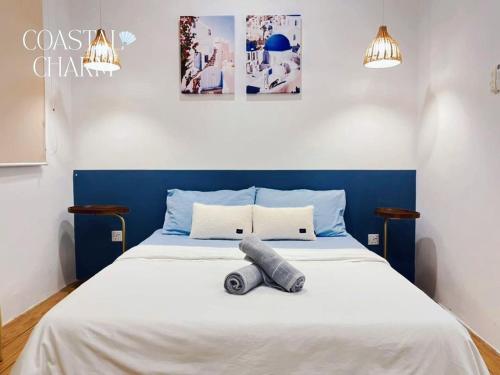 a bed with a blue headboard with a pillow on it at ITCC Manhattan Suites By Coastal Charm in Penampang