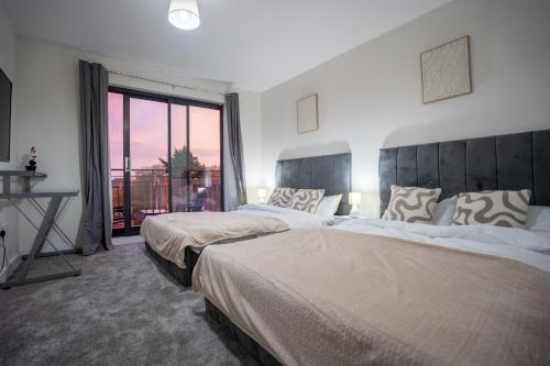 zwei Betten in einem Zimmer mit großem Fenster in der Unterkunft Penthouse in Central Nottingham with Hot tub and Games in Nottingham