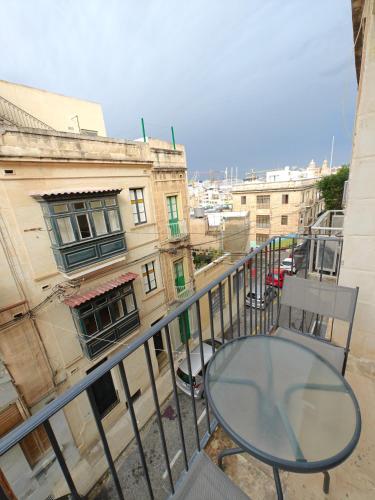 un tavolo di vetro e una sedia su un balcone con edifici di Birgu 3 a Cospicua