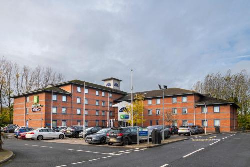 a parking lot with cars parked in front of a building at Holiday Inn Express Droitwich Spa by IHG in Droitwich