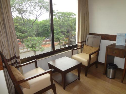 a room with two chairs and a table and a window at The Legend Inn @Nagpur in Nagpur