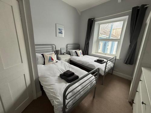 two twin beds in a small room with a window at Perfect base for 8, pets allowed in Tenby