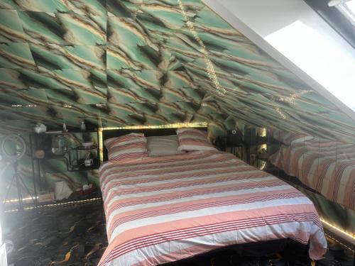 a bed in a room with a wall covered in leaves at Appartement dans la Résidence le Chateaux in Fitz-James
