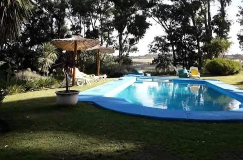 a large blue swimming pool with an umbrella at Casa del campo in Mar del Plata