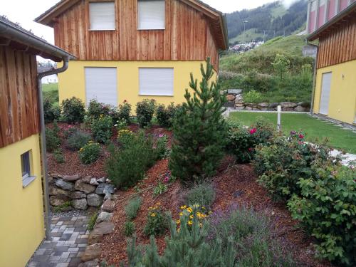 a garden in front of a yellow house at Feriendorf Uorsin in Scuol