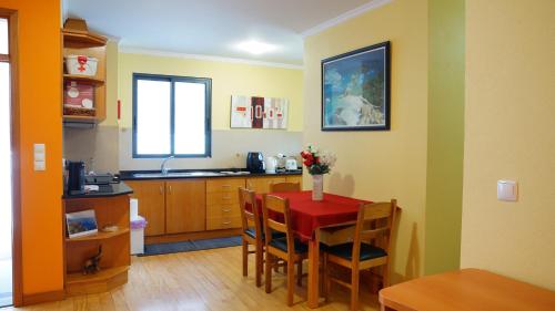 a kitchen with a red table and chairs in a room at Apartamento Barros in Estreito de Câmara de Lobos
