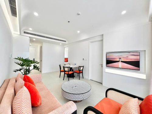 un salon avec un canapé et une télévision sur un mur dans l'établissement Atermis Regency Hillside Phu Quoc - Sea & Fireworks view- Gym & Pool Access, à Duong Dong
