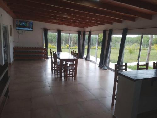 ein Esszimmer mit Tisch und Stühlen und Fenstern in der Unterkunft Los Cardales Casa Quinta con Pileta in Esquina