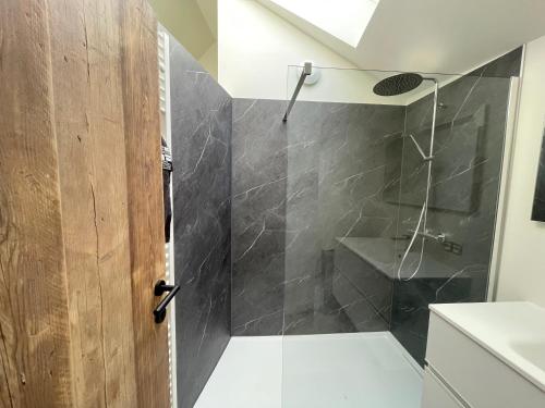een badkamer met een douche met een glazen deur bij Le Gîte du Pèlerin avec piscine in Florennes