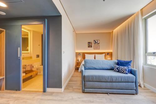 カラグアタトゥーバにあるHampton By Hilton Caraguatatuba Serramarの青いソファとベッドが備わる客室です。