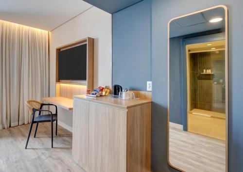 カラグアタトゥーバにあるHampton By Hilton Caraguatatuba Serramarの机と鏡のあるホテルの部屋