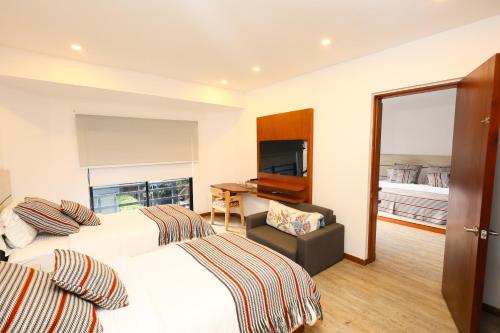 a hotel room with two beds and a desk at Hotel Casa PARDO Boutique in Bogotá