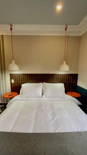 a bedroom with a white bed with two lights above it at Bendito Hostels in Bogotá