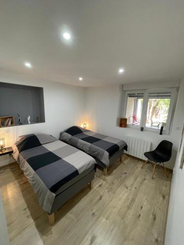 a bedroom with two beds and a chair in it at Appartement agréable et moderne - Rez de chaussée - Blainville Sur L'Eau in Blainville-sur-lʼEau