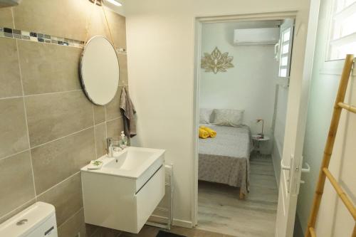 a bathroom with a sink and a mirror and a bed at Milo Cosy T2 climatisé à 2 mn de la plage du 972 in Sainte-Luce