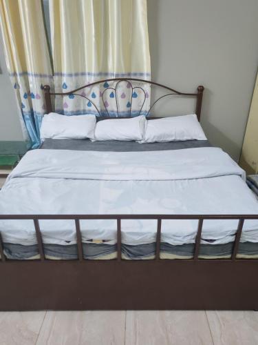a bed with a metal frame and white sheets and pillows at Atiaf Jabal Shams house in Misfāh