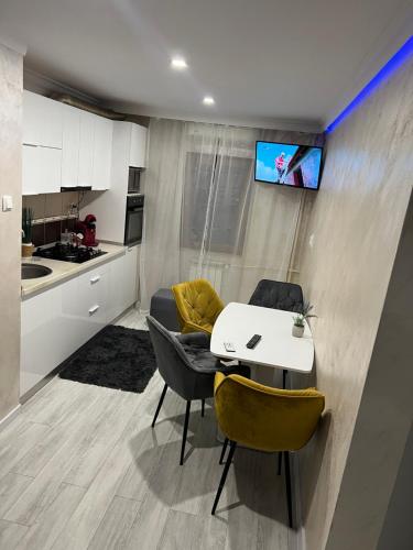a kitchen with a table and chairs and a tv on a wall at Relax Loft in Oradea