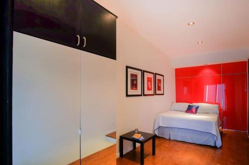 ein Schlafzimmer mit einem Bett und einer roten Wand in der Unterkunft Lovely and Cozy Apartment in Colonia Cañón Doña Petra