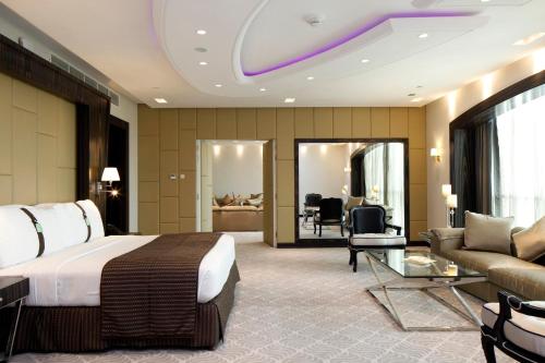 リヤドにあるホリデイ イン メイダンのベッドとリビングルームがあるホテルの部屋