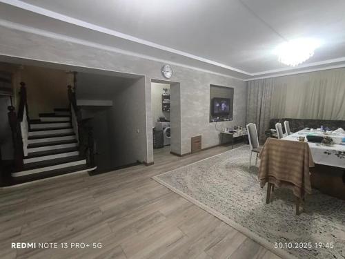 a living room with a dining table and a staircase at Екохостел in Bishkek