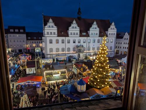 a christmas market in front of a building with a christmas tree at Ferienwohnung Marktblick direkt am Wittenberger Weihnachtsmarkt in Lutherstadt Wittenberg