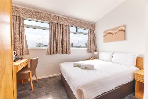 a hotel room with a bed and a desk and window at Dene Rooms in Newcastle upon Tyne