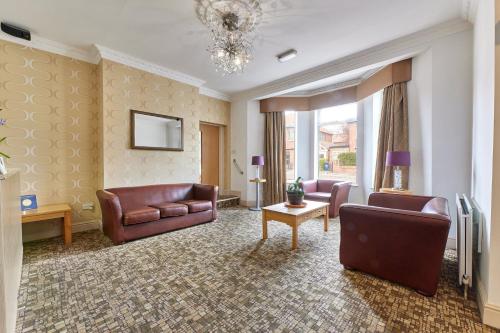 a living room with leather furniture and a chandelier at Dene Rooms in Newcastle upon Tyne