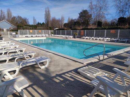 ein Swimmingpool mit Liegestühlen und ein Swimmingpool in der Unterkunft Mobilhome cosy, spacieux au bord de l'Eure in Ivry-la-Bataille