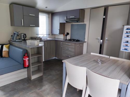 eine Küche mit einem Holztisch und weißen Stühlen in der Unterkunft Mobilhome cosy, spacieux au bord de l'Eure in Ivry-la-Bataille