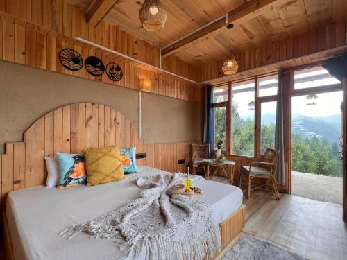 a bedroom with a bed in a room with windows at The Hidden Cabins in Jibhi