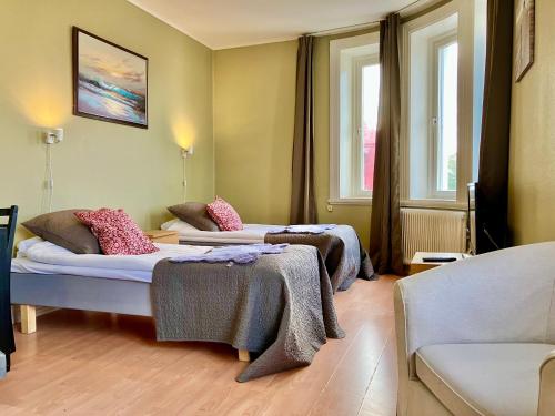 two beds in a room with two windows at Grand Hotell Strömsund in Strömsund