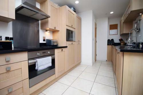 a kitchen with wooden cabinets and a stove top oven at The Cardiff Central Pad – Stylish 2-Bed Apartment in Cardiff