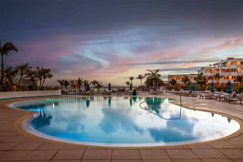 a large swimming pool with chairs and palm trees at Royal Islander Club Resort La Terrasse in Lowlands