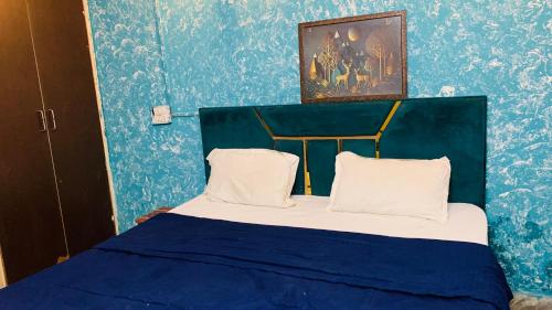 a blue bedroom with a bed with two pillows at Glory hotel in Noida