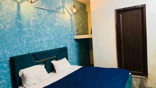 a blue bedroom with a bed with two white pillows at Glory hotel in Noida