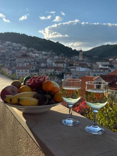 two glasses of wine on a table with a bowl of fruit at Pucisca Vero Apartments in Pučišća