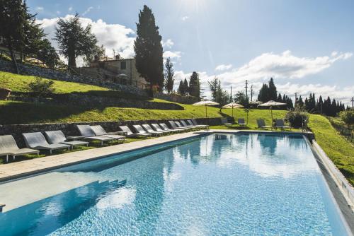 uma grande piscina com cadeiras e guarda-sóis em Borgo Di Pietrafitta Relais em Castellina in Chianti