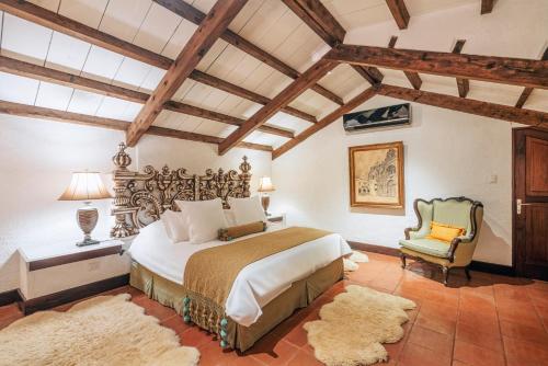 a bedroom with a large bed and a chair at Las Cruces Boutique Hotel in Antigua Guatemala